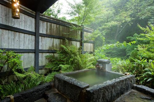 a stone fountain in the middle of a garden at Kurokawa Onsen Oku no Yu in Minamioguni