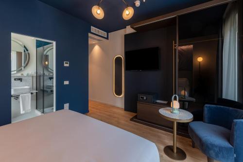 um quarto de hotel com uma cama, um sofá e uma televisão em Boutique Hotel Martini 17 em Milão