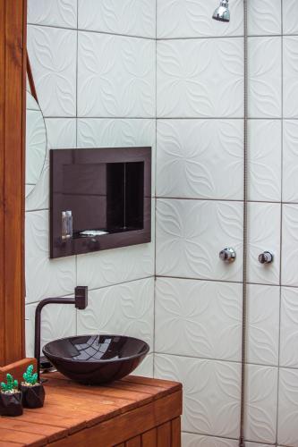 a bathroom with a black sink and a tiled wall at Império Cabanas in Urubici