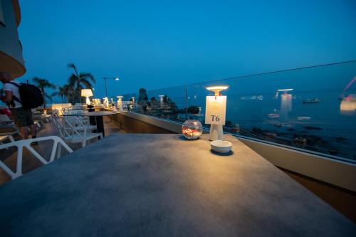 a table on a balcony with a view of the ocean at Grand Hotel Faraglioni in Acitrezza