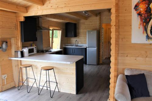 a kitchen in a log cabin with a counter and stools at Stunning 5-Bed Cabin in Ashton Under Hill in Evesham