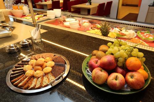 a counter with a bowl of fruit and a plate of food at Hotel Silberhorn in Nürnberg