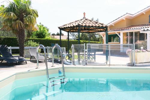a swimming pool with chairs and a gazebo at Villa Marguerite in Coutras