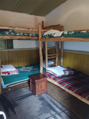 a room with two bunk beds and a table at Хижа Ловна в Рила in Panichishte