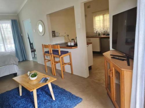 a living room with a television and a table and a kitchen at Lovely 1 Queen bed, 1 Sleeper couch Self-catering cottage in Kloof
