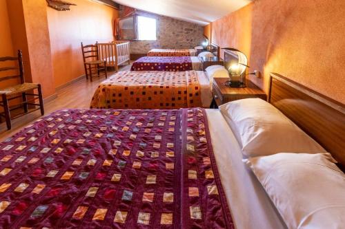 Un grupo de 4 camas en una habitación en Mas Roca Casa rural en entorno único en Girona