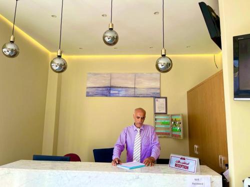 a man sitting at a table with a book at Appart Hôtel Pyramides El Jadida in El Jadida