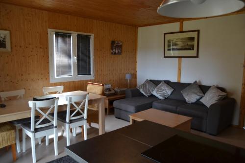a living room with a couch and a table at Beautiful lake view 3 bedroom chalet. in Saint-Manvieu-Bocage