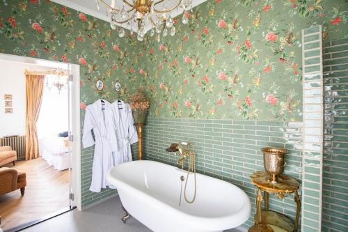 a bath tub in a bathroom with floral wallpaper at Hotellerie Het Wapen Van Athlone in De Steeg