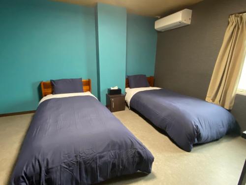 2 camas en una habitación con paredes azules en GUESTHOUSE富士と碧, en Fuji