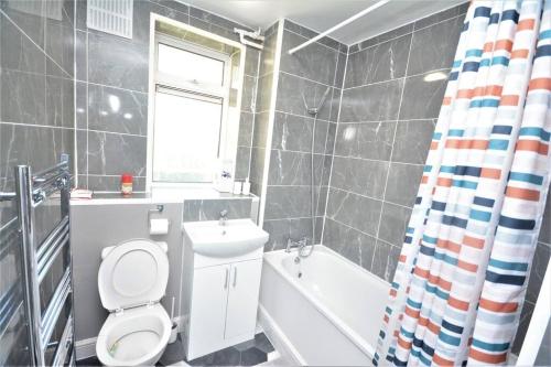 a bathroom with a toilet and a sink and a tub at London Zone 2 Two Bedroom Apartment in London