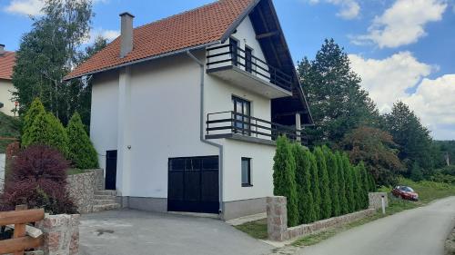 a white house with a black gate and a driveway at Kuća sa pogledom na Tornik in Zlatibor