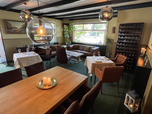 um restaurante com mesas, cadeiras e garrafas de vinho em De Herberg van Anderen em Anderen