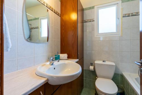 uma casa de banho com um lavatório, um WC e um espelho. em Melograno 3-BR Apt w/ Terrace in Larnaca em Lárnaca