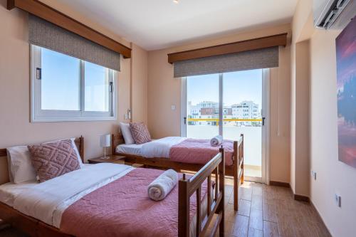 um quarto com 2 camas e uma grande janela em Melograno 3-BR Apt w/ Terrace in Larnaca em Lárnaca