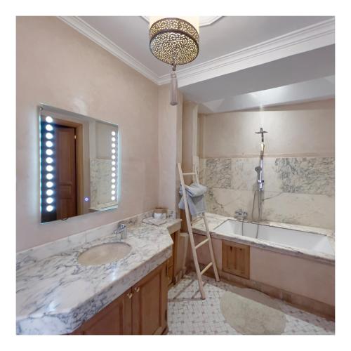 a bathroom with a sink and a mirror and a tub at Palais Nejma oriental in Marrakesh