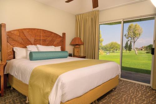 a bedroom with a large bed and a large window at Paniolo Greens Resort in Waikoloa