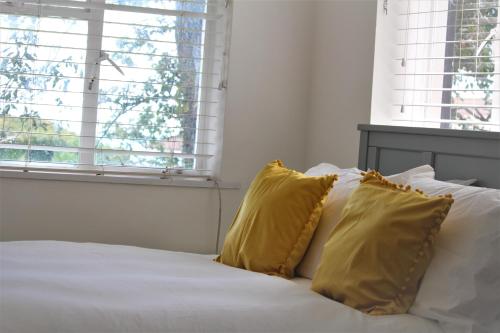 a white bed with two yellow pillows on it at Warwick House - Stunning house with terrace and sea views, sleeps 11 in Worthing