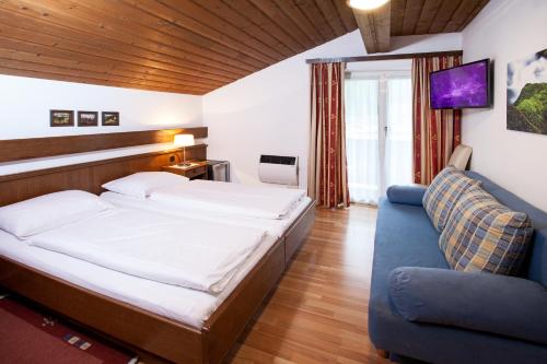 ein Schlafzimmer mit einem großen Bett und einem blauen Sofa in der Unterkunft Gästehaus Sunkler in Golling an der Salzach