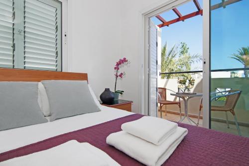 1 dormitorio con 1 cama grande y balcón en Villa Palm, en Protaras
