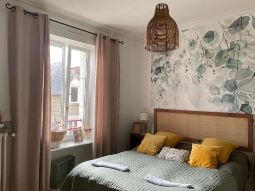 Un dormitorio con una cama con almohadas amarillas y una ventana en Les Hirondelles de la villa des roses en Pontmain