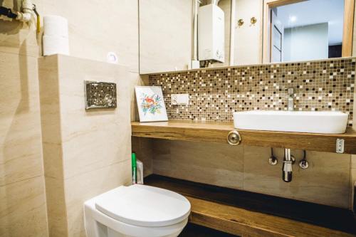 a bathroom with a white toilet and a sink at Apartament przy parku in Radom