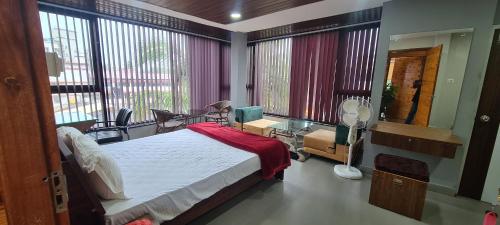 a bedroom with a bed and a living room with windows at RK 2 and 3 bedroom penthouse in Panaji