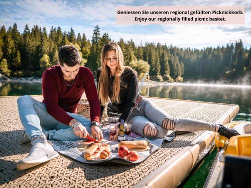 a man and woman sitting on a dock with a tray of food at Romantik Hotel Schweizerhof & Spa Flims in Flims