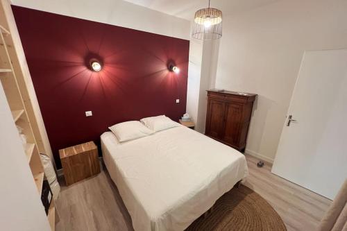 a bedroom with a white bed with a red wall at LE FIGUIER - CLIM - WIFI in Villeneuve-lès-Avignon