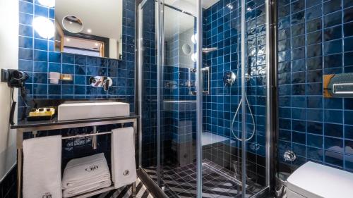 a blue tiled bathroom with a shower and a sink at The Gift Hotel in Istanbul