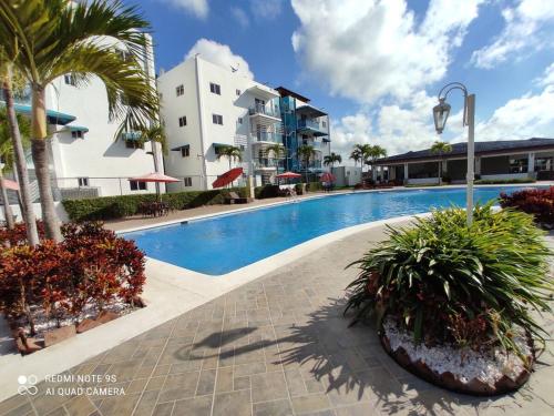 a swimming pool with palm trees and a building at Caribean Dreams Apartement Beautiful Pool and Gym in Santiago de los Caballeros