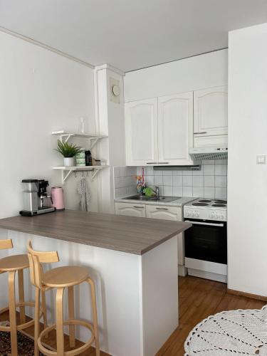 圖爾庫的住宿－Lämminhenkinen yksiö Port Arthurissa，白色的厨房配有白色橱柜和带凳子的柜台