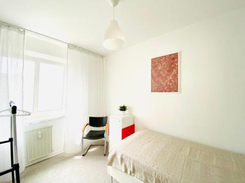 a white bedroom with a bed and a chair at HannoverMesseApartment 2 bedroom in Hannover