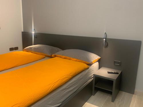 łóżko z pomarańczową pościelą i stolikiem. w obiekcie Rivacentro 2 w mieście Riva del Garda