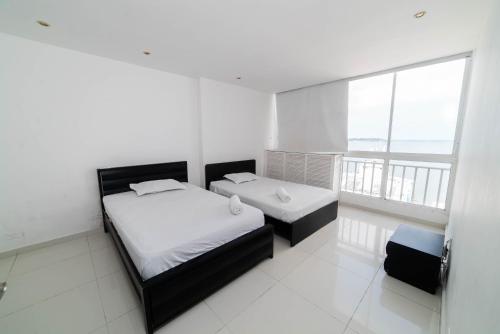 Habitación blanca con 2 camas y ventana grande. en Cozy Apartment in El Laguito, en Cartagena de Indias