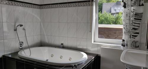 baño con bañera, lavabo y ventana en Ferienhaus Schulte - Villa Jupp und Apartment Liesl, en Olsberg
