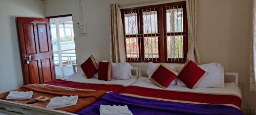 a bedroom with two beds with red and white pillows at Redstone House by Oxystays Hospitality in Ganpatipule