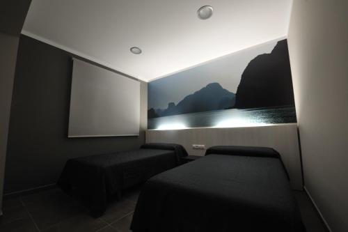 a room with two beds and a projection screen at Aparthotel Meseguer in Alcañiz