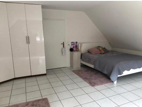 a bedroom with a bed and white cabinets and a tiled floor at Schönes grosses Haus an der Grenze zur Schweiz und Frankreich in Weil am Rhein