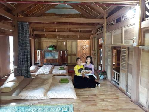 two women sitting on a bed in a room at Thao Ly Homestay Mai Chau in Hòa Bình