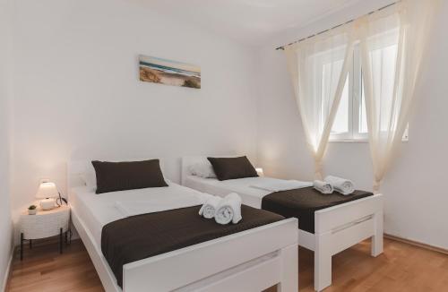 two beds in a bedroom with white walls and windows at Apartments by the sea Molat - 18433 in Molat