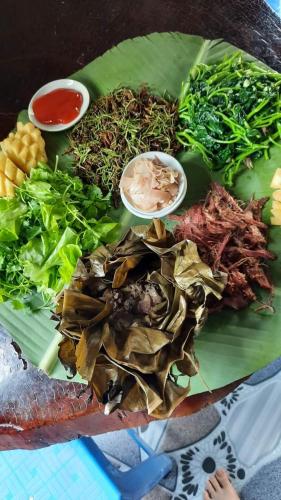 a green plate of food with vegetables and sauce at Thao Ly Homestay Mai Chau in Hòa Bình