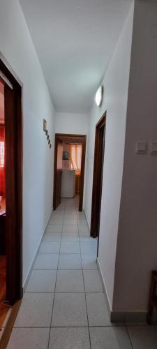 a hallway with white walls and a white tile floor at Central Residence in Ploieşti