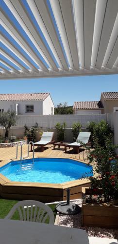 einen Pool auf einer Terrasse mit Stühlen und einem Tisch in der Unterkunft Chez Valérie in Vergèze