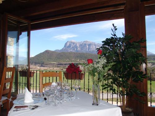 a table with a white table cloth with a view of a mountain at Hotel & SPA Peña Montañesa in Aínsa