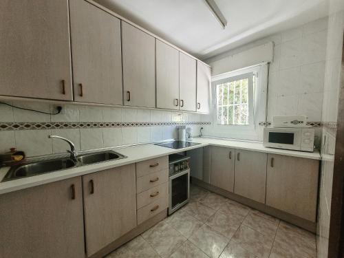 uma cozinha com armários brancos, um lavatório e um micro-ondas em Casa rural Balcón de Monachil em Monachil