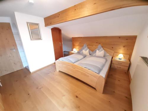 a bedroom with a wooden bed with white pillows at Gästehaus Frankl in Rottau
