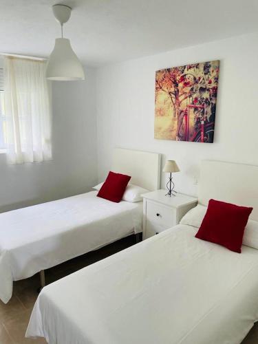 two beds with red pillows in a room at APARTAMENTO PLAYA DE ESTORDE in Cee