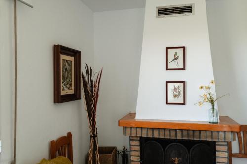 a living room with a fireplace and pictures on the wall at Casa rural Balcón de Monachil in Monachil