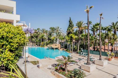 a view of a pool at a resort with palm trees at Guadalpin Suites in Marbella
